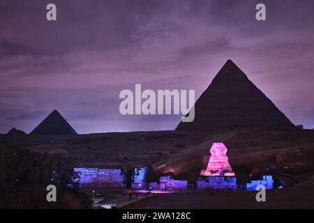 Giza, Egitto - 24 dicembre 2023: Le piramidi e la Sfinge nelle luci notturne Foto Stock