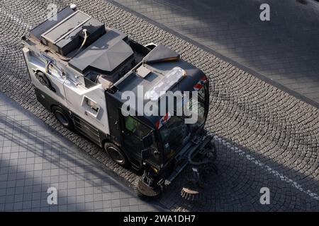 La macchina per la pulizia stradale raccoglie rifiuti, rifiuti e foglie, viste dall'alto. Spazzatrice stradale e pulizia Foto Stock