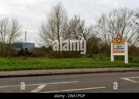 Cartello del grande villaggio di Blakenham con l'energia proveniente dalla struttura dei rifiuti sullo sfondo, Great Blakenham, Suffolk dicembre 2023 Foto Stock