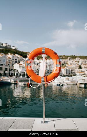 Lifebuoy su un piedistallo con chiavistello si trova sulla riva della baia di Lustica. Montenegro Foto Stock