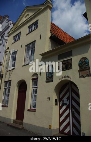 Casa cittadina con arco decorata con murales e porte dipinte a chevron, Lubeck, Germania Est Foto Stock