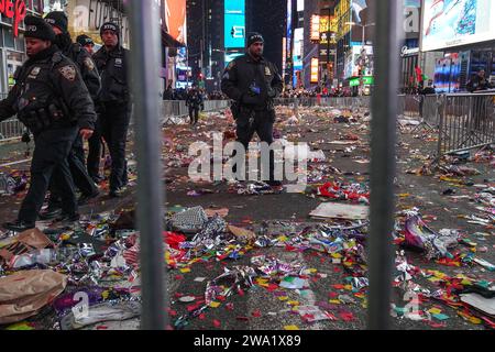 New York, Stati Uniti. 1 gennaio 2024. Gli agenti di polizia camminano a Times Square quando i coriandoli e i detriti gettati a terra. Dopo la tradizionale celebrazione del conto alla rovescia e l'iconica caduta della palla a Times Square, le conseguenze rivelano una scena cosparsa di resti di coriandoli e detriti scartati. Subito dopo la rivelazione, il Dipartimento di Sanitazione della città di New York (DSNY) mobilita un team dedicato di operai per la pulizia per affrontare rapidamente il gigantesco compito di riportare Times Square al suo stato incontaminato. Credito: SOPA Images Limited/Alamy Live News Foto Stock