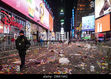 New York, Stati Uniti. 1 gennaio 2024. Un agente di polizia cammina a Times Square quando i coriandoli e i detriti gettati a terra. Dopo la tradizionale celebrazione del conto alla rovescia e l'iconica caduta della palla a Times Square, le conseguenze rivelano una scena cosparsa di resti di coriandoli e detriti scartati. Subito dopo la rivelazione, il Dipartimento di Sanitazione della città di New York (DSNY) mobilita un team dedicato di operai per la pulizia per affrontare rapidamente il gigantesco compito di riportare Times Square al suo stato incontaminato. Credito: SOPA Images Limited/Alamy Live News Foto Stock