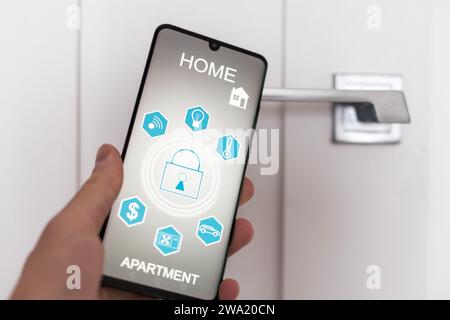 Il bloccaggio smartlock sulla porta di ingresso utilizzando un telefono intelligente in remoto. Concetto di utilizzo di smart serrature elettroniche con sistema di accesso senza chiave Foto Stock