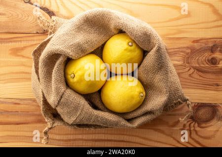 Tre limoni maturi gialli in una borsa di iuta , primo piano, vista dall'alto. Foto Stock