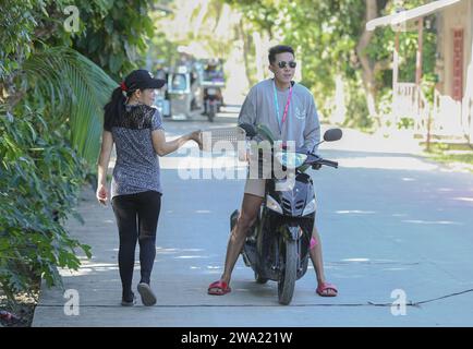 Tiaong, Filippine. 1 gennaio 2024: Nelle province rurali, le famiglie povere filippine costruiscono strade a pedaggio amichevoli con una corda e un cartello di felice anno nuovo. Auto, tricicli o pedoni sono incoraggiati a fare donazioni "grazie", generalmente solo pochi pesos, senza impegno, sempre con sorriso e talvolta abbelliti da pochi passi di danza. Una tradizione che era praticata solo in alcune regioni e che si è diffusa in quasi tutto il paese dai giorni duri dell'epidemia di COVID 19. Ad esempio, oltre 1 km, in alcuni luoghi è possibile contare fino a quindici fermate. Crediti: Kevin Izorce/Alamy Live News Foto Stock