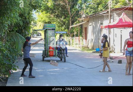 Tiaong, Filippine. 1 gennaio 2024: Nelle province rurali, le famiglie povere filippine costruiscono strade a pedaggio amichevoli con una corda e un cartello di felice anno nuovo. Auto, tricicli o pedoni sono incoraggiati a fare donazioni "grazie", generalmente solo pochi pesos, senza impegno, sempre con sorriso e talvolta abbelliti da pochi passi di danza. Una tradizione che era praticata solo in alcune regioni e che si è diffusa in quasi tutto il paese dai giorni duri dell'epidemia di COVID 19. Ad esempio, oltre 1 km, in alcuni luoghi è possibile contare fino a quindici fermate. Crediti: Kevin Izorce/Alamy Live News Foto Stock