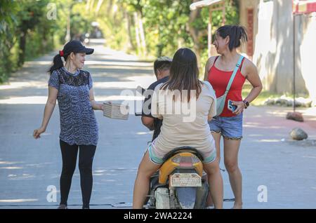 Tiaong, Filippine. 1 gennaio 2024: Nelle province rurali, le famiglie povere filippine costruiscono strade a pedaggio amichevoli con una corda e un cartello di felice anno nuovo. Auto, tricicli o pedoni sono incoraggiati a fare donazioni "grazie", generalmente solo pochi pesos, senza impegno, sempre con sorriso e talvolta abbelliti da pochi passi di danza. Una tradizione che era praticata solo in alcune regioni e che si è diffusa in quasi tutto il paese dai giorni duri dell'epidemia di COVID 19. Ad esempio, oltre 1 km, in alcuni luoghi è possibile contare fino a quindici fermate. Crediti: Kevin Izorce/Alamy Live News Foto Stock