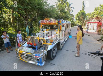 Tiaong, Filippine. 1 gennaio 2024: Nelle province rurali, le famiglie povere filippine costruiscono strade a pedaggio amichevoli con una corda e un cartello di felice anno nuovo. Auto, tricicli o pedoni sono incoraggiati a fare donazioni "grazie", generalmente solo pochi pesos, senza impegno, sempre con sorriso e talvolta abbelliti da pochi passi di danza. Una tradizione che era praticata solo in alcune regioni e che si è diffusa in quasi tutto il paese dai giorni duri dell'epidemia di COVID 19. Ad esempio, oltre 1 km, in alcuni luoghi è possibile contare fino a quindici fermate. Crediti: Kevin Izorce/Alamy Live News Foto Stock