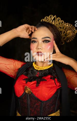 Una ballerina sundanese che indossa gioielli d'oro che dona un tocco di lusso al suo aspetto sul palco di notte Foto Stock