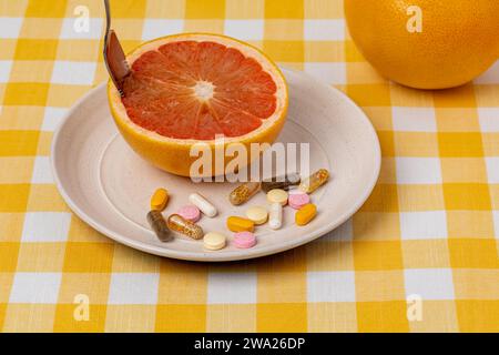 Pompelmo tagliato su piatto con vitamine e integratori alimentari. Frutta biologica, dieta sana e concetto nutrizionale. Foto Stock