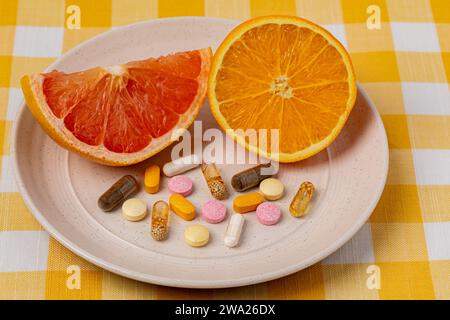 Arancia e pompelmo a fette in piatto con vitamine e integratori alimentari. Frutta biologica, dieta sana e concetto nutrizionale. Foto Stock