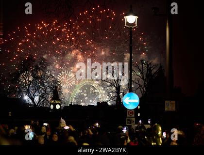 31 dic 2023 - LondonUK : immagine di strada di Capodanno fuochi d'artificio sopra l'occhio di londra e grande ben con sfocato primo piano di persone con cellule mobili Foto Stock