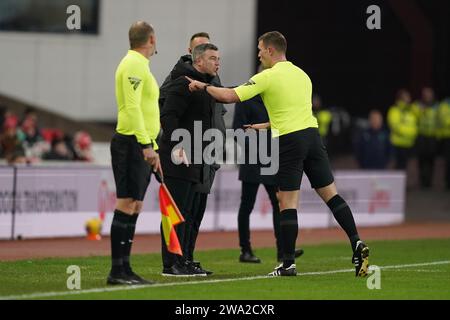 L'arbitro Thomas Bramall (a destra) parla con il manager dello Stoke City Steven Schumacher (al centro) durante la partita del campionato Sky Bet al Bet365 Stadium, Stoke-on-Trent. Data immagine: Lunedì 1 gennaio 2024. Foto Stock