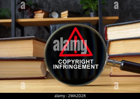 Libri e lente d'ingrandimento con iscrizione violazione del copyright. Foto Stock