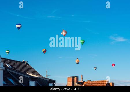 Bunte Heißluftballons über den Dächern der Kieler Altstadt vor blauem Himmel im Sommer Foto Stock