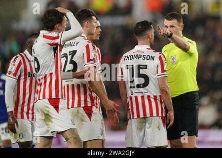 L'arbitro Thomas Bramall manda Jordan Thompson di Stoke City (secondo da destra) durante il match per lo Sky Bet Championship al Bet365 Stadium, Stoke-on-Trent. Data immagine: Lunedì 1 gennaio 2024. Foto Stock