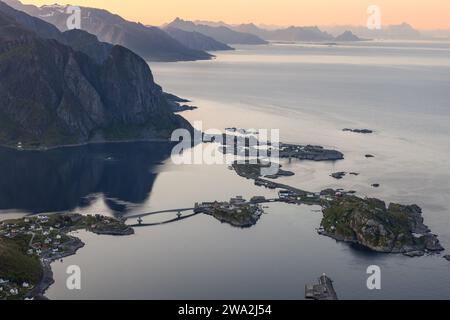 La luce serale si ammorbidisce sul suggestivo paesaggio delle Lofoten, mentre le isole di Reine interconnesse si riflettono nelle acque del fiordo Foto Stock