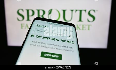 Smartphone con sito Web dell'azienda statunitense di vendita al dettaglio Sceuts Farmers Market Inc. Davanti al logo aziendale. Mettere a fuoco in alto a sinistra sul display del telefono. Foto Stock