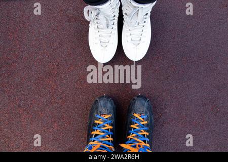 Le ragazze stanno in piedi sui pattini per strada in inverno, pattinaggio dall'alto verso il basso, due gambe sulla strada sui pattini, amicizia, insieme Foto Stock