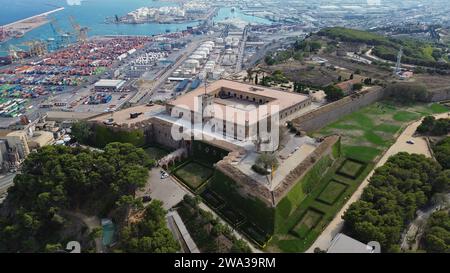 Riprese aeree con drone dello Château de Montjuïc a Barcellona, Spagna, bastioni di una fortezza militare del XVII secolo, torri di guardia e panorama del porto mediterraneo Foto Stock