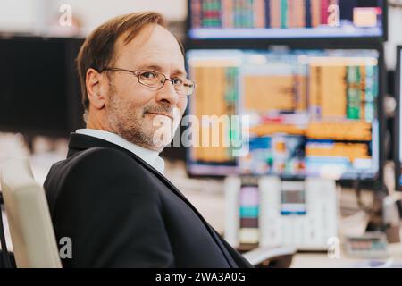 Uomo che lavora in sala di scambio, trader in ufficio Foto Stock