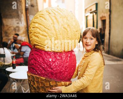 Divertente ritratto di una bella bambina con un gelato gigante Foto Stock