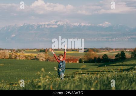 Graziosa bambina che gioca all'aperto nei campi svizzeri con vista sul lago di Ginevra e sulle montagne francesi dell'alta Savoia. Immagine scattata nella zona di Losanna, cantone di Foto Stock