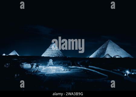 Giza, Egitto - 24 dicembre 2023: Le piramidi e la Sfinge nelle luci notturne Foto Stock