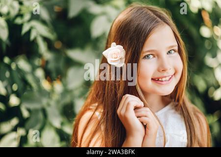 Ritratto all'aperto di adorabile bambina con fiore di rosa bianco Foto Stock