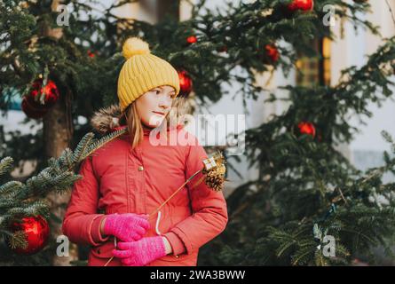 Bambina felice che gioca con l'albero di Natale per le strade della vecchia città europea in vacanza, con immagini per bambini scattate a Losanna, Svizzera Foto Stock