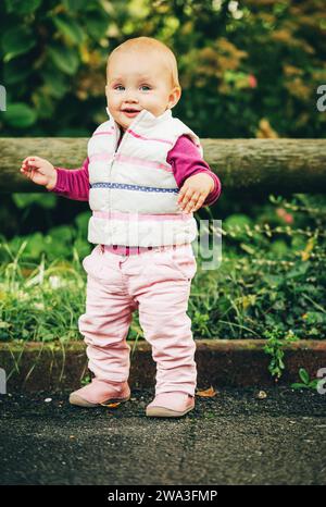 Ritratto all'aperto di adorabile bambina di 9-12 mesi che gioca nel parco, indossando un bodymer bianco Foto Stock