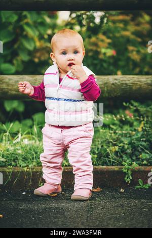 Ritratto all'aperto di adorabile bambina di 9-12 mesi che gioca nel parco, indossando un bodymer bianco Foto Stock