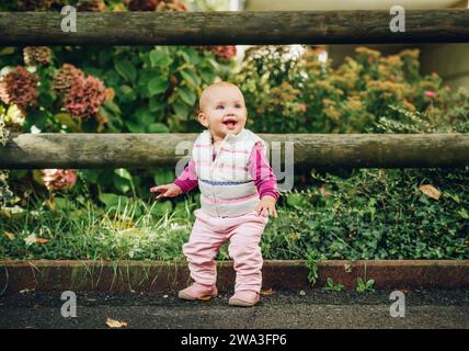 Ritratto all'aperto di adorabile bambina di 9-12 mesi che gioca nel parco, indossando un bodymer bianco Foto Stock