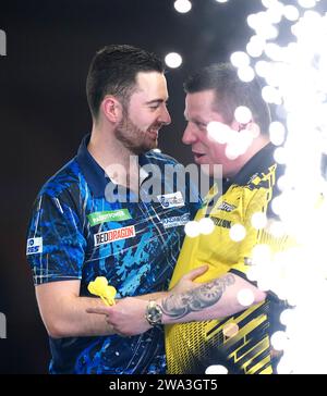 Luke Humphries celebra la vittoria su Dave Chisnall (a destra) nel giorno quattordicesimo del Paddy Power World Darts Championship all'Alexandra Palace di Londra. Data immagine: Lunedì 1 gennaio 2024. Foto Stock