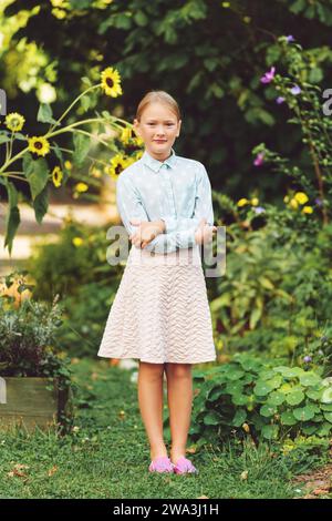 Ritratto alla moda di una graziosa bambina all'aperto, che indossa una camicia verde chiaro e una gonna rosa Foto Stock