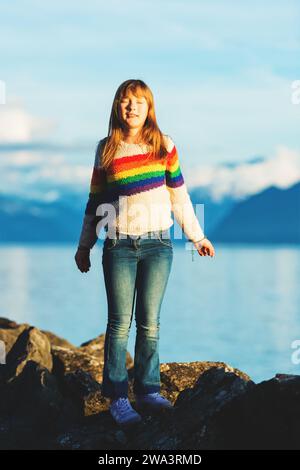 Bambina felice e giovane che gioca vicino al lago di ginevra al tramonto, braccia spalancate Foto Stock