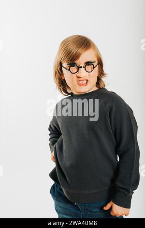 Foto in studio di un bambino divertente su sfondo bianco, che indossa occhiali di plastica con finti cervelli e naso Foto Stock