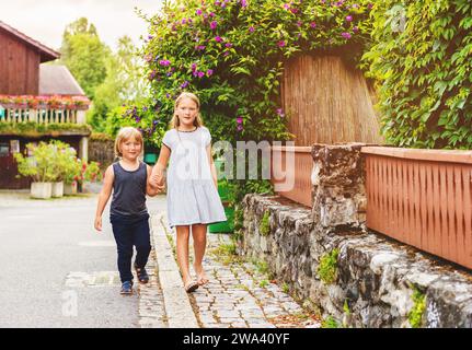 Due ragazzi che camminano lungo la strada, tenendosi per mano Foto Stock