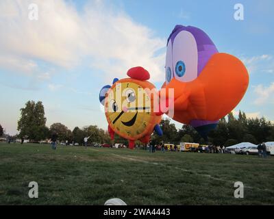Mongolfiera a forma di uccello che bacia una mongolfiera a forma di sveglia al Walla Walla Hot Air Balloon Festival. Foto Stock