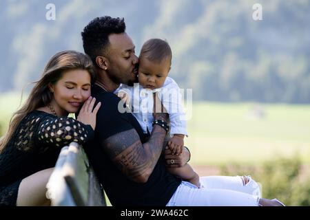 Genitori multietnici bambino birazziale nel parco. Ritratto di coppia multirazziale all'aperto. Bambino birazziale con i genitori nel cortile. Famiglia eterogenea. Africano Foto Stock