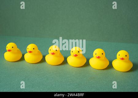 Fila di anatra in gomma gialla su sfondo verde. concetto di leadership del lavoro di squadra Foto Stock