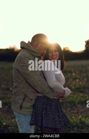 L'uomo abbraccia la sua ragazza al tramonto, circondato da un ambiente naturale. Foto Stock