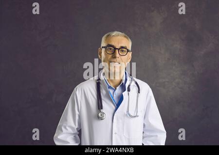 Ritratto in studio di un serio medico maschile anziano in occhiali e cappotto medico bianco Foto Stock