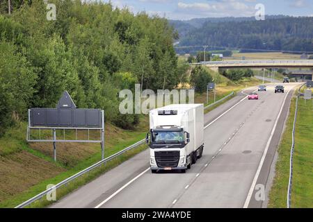 L'autocarro Volvo FH bianco con rimorchio refrigerato consegna merci sull'autostrada E18 in un giorno d'estate con vista elevata. Salo, Finlandia. 24 agosto 2023. Foto Stock