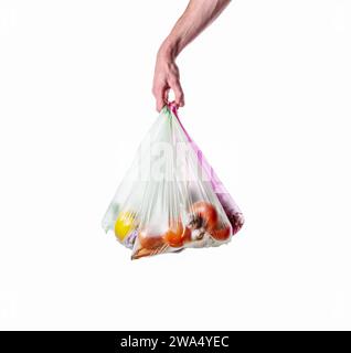 Un uomo tiene in mano dei sacchetti di plastica con delle verdure su sfondo bianco. Inquinamento ambientale dovuto alla plastica. Isolato su sfondo bianco. Foto Stock