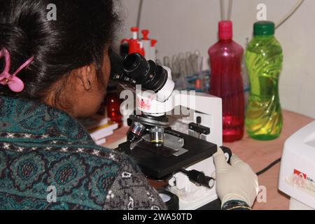 Lady patologa che sta esaminando con il microscopio. India Foto Stock