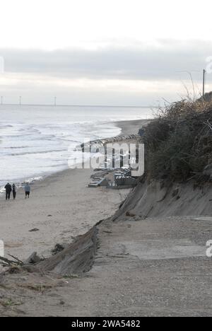 Vista del bordo della Access Road sul Marrams che è crollato a causa dell'erosione costiera, con persone che camminano sulla spiaggia verso le difese del mare di Hex Block. Foto Stock