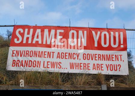 Banner legato su recinzione vicino a Hemsby Gap, che menziona il deputato locale e le autorità a rischio di inondazione in relazione all'erosione costiera. Foto Stock