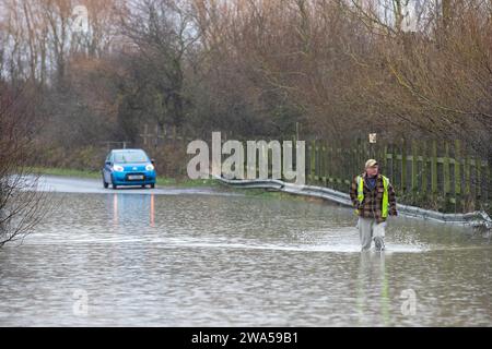 Un uomo cammina attraverso la strada allagata causata da tempeste e forti piogge nei pressi di Leeds su Newton Lane, Fairburn, Castleford, Regno Unito, 2 gennaio 2024 (foto di James Heaton/News Images) Foto Stock